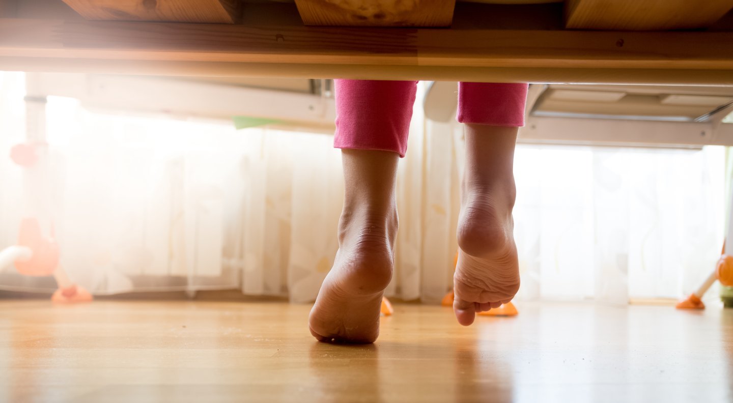 rear view of feelt hitting wooden floor, getting out of bed