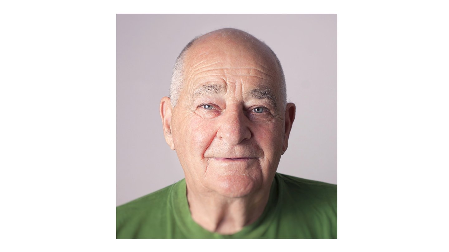 Older white man smiling with a green shirt