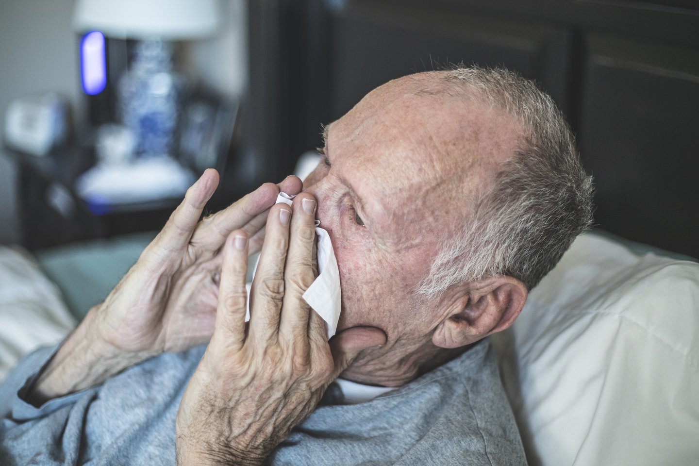 elderly man blowing his nose