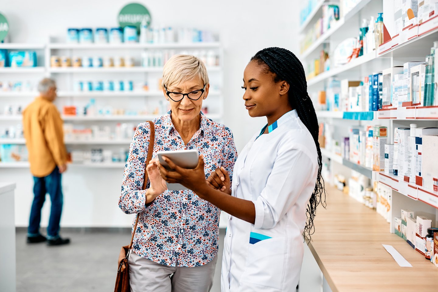 Pharmacist explains something to an elderly woman