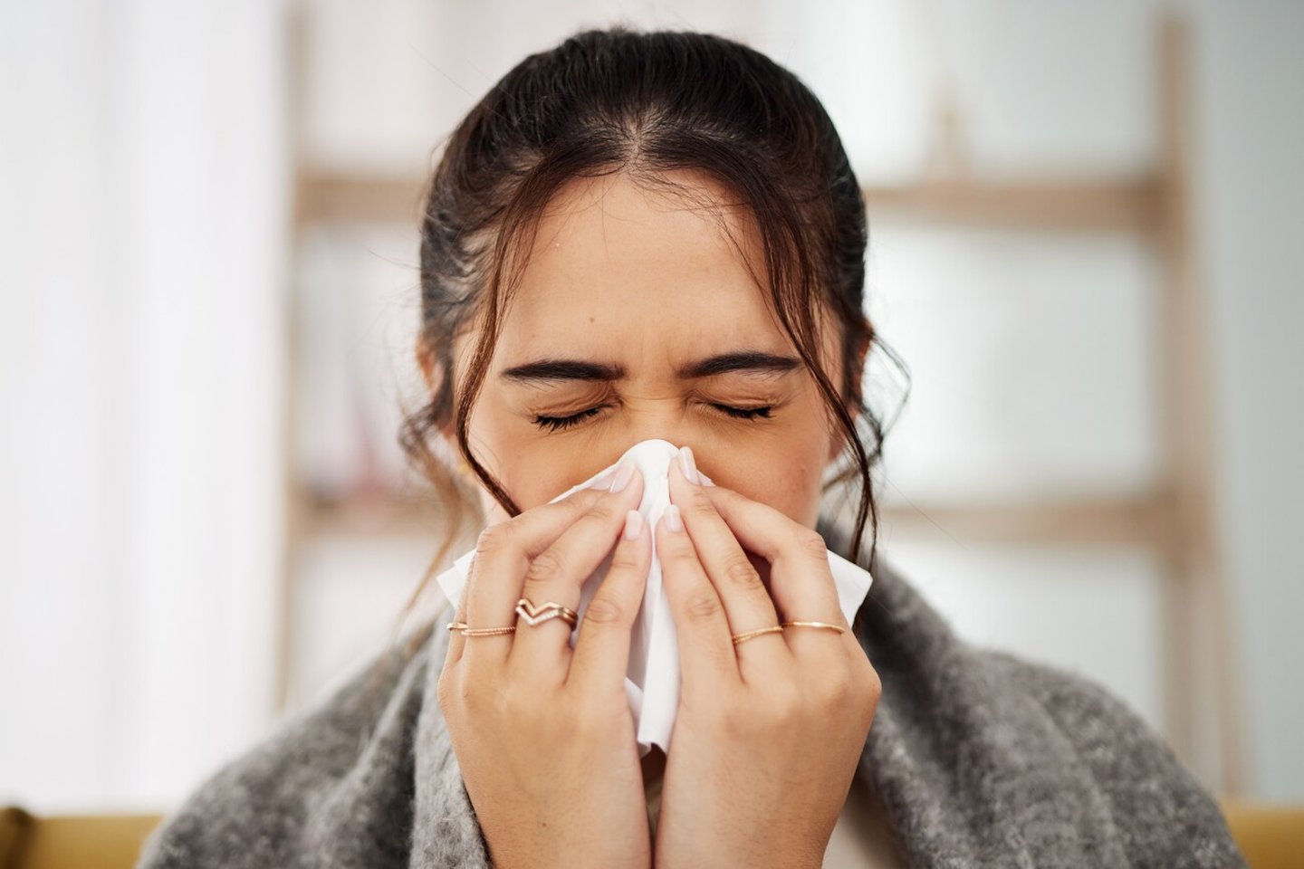 Tissue, nose and sick woman sneezing in living room with allergy, cold or flu in her home. Hay fever, sinusitis and female with viral infection, risk or health crisis in lounge with congestion; Shutterstock ID 2338427615