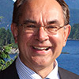 a man wearing a suit and tie smiling at the camera