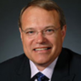 a man wearing a suit and tie smiling at the camera