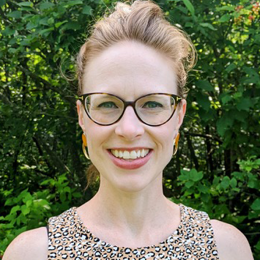 a woman wearing glasses and smiling at the camera