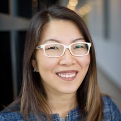 a woman wearing glasses and smiling at the camera