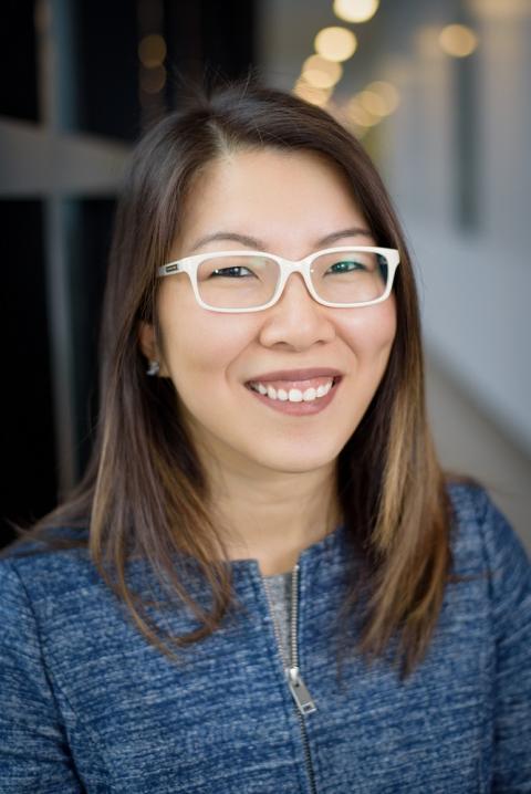 a woman wearing glasses and smiling at the camera